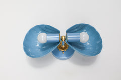 A tight close-up of the slate blue Double Coquille sconce, focused on the scalloped shell texture and brass rosette hardware. Good for anyone comparing finish and detail on a coastal bathroom or Southern traditional powder room sconce.