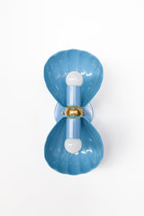 A wide, opened-out view of the slate blue Double Coquille sconce, showing how the two fluted shell shades and brass rosette connect at the center. A helpful reference for seeing the full construction and hardware detail before choosing a coastal or scalloped sconce for a bathroom or powder room.