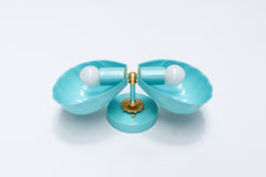 Double Coquille sconce in poolside turquoise with brass hardware, close front crop showing the fluted scalloped edges of both shell shades and the brass floral rosette mount, unlit with exposed white bulbs.