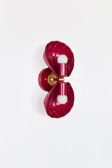Double Coquille wall sconce in glossy Black Cherry, a deep wine-red finish that reads like lacquered candy. Two sculptural scallop shells frame the bulbs and create a symmetrical, Art Deco silhouette, with warm brass details at the center for a hint of vintage glamour. Shot straight-on against a clean white background, this image is ideal for searches like shell sconce, scallop shell wall light, coastal glam lighting, boutique hotel bathroom sconce, statement powder room lighting, and colorful brass wall sc