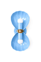 A double wall sconce built from two fluted, shell-form shades in a soft hydrangea blue, joined by an ornate brass floral rosette at the center. The scalloped shape reads coastal without tipping into beachy cliché, which makes it just as at home in an English coastal cottage or a Southern traditional powder room as it is in a fully maximalist, pattern-on-pattern bathroom. Layer it against striped wallpaper for a grandmillennial feel, or let it stand alone against a plain wall in a more restrained coastal tra