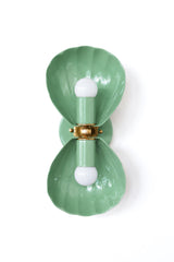 A double wall sconce in a soft, sage-leaning vista green, with two fluted shell shades meeting at an ornate brass floral rosette. This is a quieter green than a bright kelly or chartreuse, which makes it a natural fit for an English cottage bathroom, a grandmillennial guest room layered with botanicals and antiques, or a coastal traditional powder room that wants organic color without going full beachy. Just as at home in a maximalist eclectic space where it plays off other greens and florals as it is stand