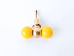 A double-ball cabinet knob pairing two glossy yellow spheres with a smaller brass ball at the center, giving it more shape than a standard single knob. A cheerful pick for a butter yellow kitchen, breakfast nook, or any cabinetry that could use one bright, happy detail.
