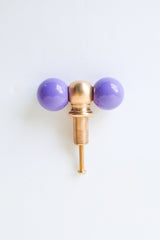 A straight-on look at the orchid and brass double-ball knob, showing the finish, proportions, and mounting hardware clearly. A useful reference for checking scale and color before installing on a dresser or vanity.
