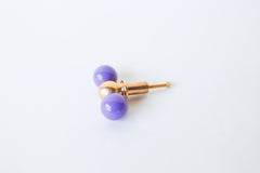 A double-ball cabinet knob pairing two glossy orchid purple spheres with a polished brass ball at the center, shown at an angle to show its full shape. A rich, feminine pick for a romantic bedroom dresser, a bold bathroom vanity, or any cabinetry that wants real color and presence.