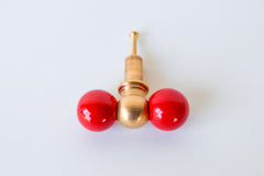 A straight-on, symmetrical view of the red and brass double-ball knob, showing the finish and mounting hardware clearly. A clear reference shot for comparing this bold colorway against your own cabinetry.