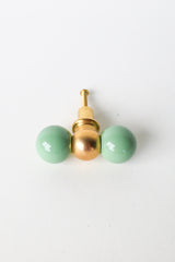 Vista green and brass double gumball knob, shown at an angle. A versatile colorful knob that suits dresser makeovers, colorful bathrooms, kitchen cabinetry, built-ins, kids' spaces, and offices alike.