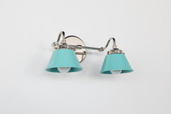 Double Kelly Sconce in Poolside blue and chrome, a small double bathroom vanity light with two powder coated steel cone shades, shown in angled view on a white wall, ideal for colorful bathroom lighting, modern bathroom wall sconce, retro bathroom light fixture, and maximalist bathroom design.