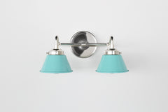 Front view of the Double Kelly Sconce in chrome with Poolside blue cone shades, a compact double wall sconce for above mirror lighting, bathroom vanity lighting, small bathroom light fixture, colorful modern sconce, mid century inspired bathroom lighting, and playful eclectic bathroom decor.
