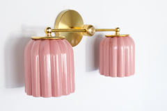 Side angle photo of the Double Marcella ceramic wall sconce showing glossy blush pink ribbed ceramic shades and a brass arm and backplate, a statement bathroom light for chinoiserie inspired spaces, pastel interiors, and classic traditional rooms that need a fun unexpected hint of color