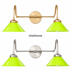 A chartreuse lime green two-light gooseneck wall sconce with glossy cone shades, shown in Chartreuse with brass or nickel hardware. It has two curved gooseneck arms joined by a straight crossbar at a round backplate, so it sits wide like a vanity light. Hang it over a bathroom mirror, above a kitchen sink, or in a powder room. Chartreuse looks sharp with navy or plum walls, black and white tile, and pink accents, so it suits maximalist, Hollywood Regency, and eclectic rooms.