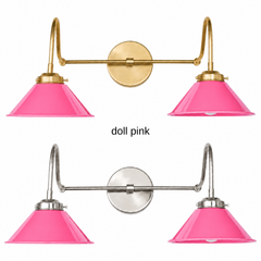 A hot pink two-light gooseneck wall sconce with glossy cone shades, shown in Doll Pink with brass or nickel hardware. It has two curved gooseneck arms joined by a straight crossbar at a round backplate, so it sits wide like a vanity light. Hang it over a bathroom mirror, above a kitchen sink, or in a powder room. Bright pink looks great against green or orange walls and bold graphic wallpaper, so it suits maximalist, playful, and pink bathroom decor.