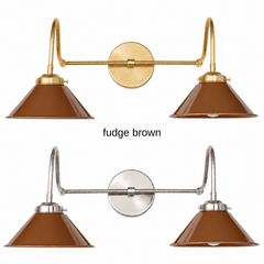 A caramel brown two-light gooseneck wall sconce with glossy cone shades, shown in Fudge Brown with brass or nickel hardware. It has two curved gooseneck arms joined by a straight crossbar at a round backplate, so it sits wide like a vanity light. Hang it over a bathroom mirror, above a kitchen sink, or over a coffee bar. Warm brown pairs well with cream, olive, and rust, plus leather and walnut, so it suits 70s inspired, mid century modern, and cozy traditional rooms.