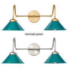 A dark teal green two-light gooseneck wall sconce with glossy cone shades, shown in Mermaid Green with brass or nickel hardware. It has two curved gooseneck arms joined by a straight crossbar at a round backplate, so it sits wide like a vanity light. Hang it over a bathroom mirror, above a kitchen sink, or over a home bar. Deep teal sits well with coral or mustard accents, velvet, and dark wood, so it suits coastal, jewel tone, and mid century modern decor.