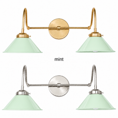 A pastel mint green two-light gooseneck wall sconce with glossy cone shades, shown in Mint with brass or nickel hardware. It has two curved gooseneck arms joined by a straight crossbar at a round backplate, so it sits wide like a vanity light. Hang it over a bathroom mirror, above a laundry room sink, or in a nursery. Pale mint looks soft with white beadboard, pink or lilac accents, and light oak, so it suits pastel, cottage, and vintage bathroom decor.