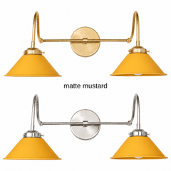 A mustard yellow two-light gooseneck wall sconce with matte cone shades, shown in Mustard with brass or nickel hardware. It has two curved gooseneck arms joined by a straight crossbar at a round backplate, so it sits wide like a vanity light. Hang it over a bathroom mirror, above a kitchen sink, or over a coffee bar. Matte mustard sits well with olive or navy walls, rattan, and warm white oak, so it suits mid century, boho, and Scandinavian rooms.