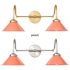 A peach coral two-light gooseneck wall sconce with glossy cone shades, shown in Peach with brass or nickel hardware. It has two curved gooseneck arms joined by a straight crossbar at a round backplate, so it sits wide like a vanity light. Hang it over a bathroom mirror, above a kitchen sink, or over a breakfast nook. Peach looks good with sage or cream walls, terracotta tile, and warm brass, so it suits coastal, cottage, and soft modern bathroom and kitchen decor.