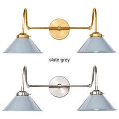 A light gray two-light gooseneck wall sconce with glossy cone shades, shown in Slate Grey with brass or nickel hardware. It has two curved gooseneck arms joined by a straight crossbar at a round backplate, so it sits wide like a vanity light. Hang it over a bathroom mirror, above a kitchen sink, or down a long hallway. Soft gray pairs well with white oak, marble, and linen, so it suits Scandinavian, transitional, and quiet modern farmhouse rooms.