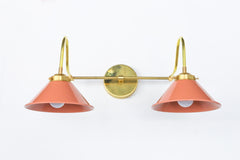 Peach and brass bathroom wall sconce with curvy arms and cone shades.  Great for large bright bathrooms and vanities