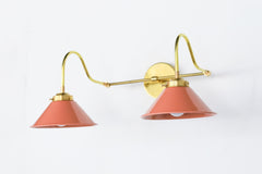 Peach and brass bathroom wall sconce with curvy arms and cone shades.  Great for large bright bathrooms and vanities