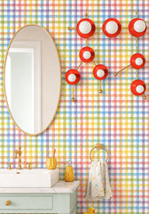 Colorful bathroom with rainbow plaid wallpaper, a large oval brass mirror, pale mint vanity, white sink, brass faucet, yellow accessories, and the Flame and Brass Gemini One sconce mounted as sculptural wall art above the vanity. The fixture’s flame-orange discs, brass constellation arms, and white globe bulbs recreate the Gemini zodiac star pattern in a playful, modern way. This bold wall sconce is perfect for maximalist bathrooms, kids bathroom lighting, colorful powder rooms, dopamine decor, astrology de