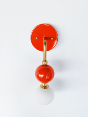 A glossy flame-orange wall sconce for a bathroom, powder room, or entryway that leads with warmth and color. The Ida sconce stacks a saturated orange powder-coated sphere over a frosted glass globe, joined by warm brass hardware and a round orange backplate. Sunny, citrusy, and unapologetically bold, it's a standout for eclectic, maximalist, and colorful traditional homes that skip the safe answer.