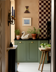 Poolside blue Clancy sconce with polished brass hardware brightens a retro-inspired bathroom with pink and orange fan-patterned wallpaper, terrazzo flooring, and a warm oak vanity. This midcentury wall light by Sazerac Stitches brings a cheerful, colorful accent that makes small bathrooms or powder rooms feel artful and custom.
