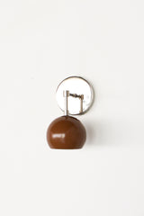 Minimalist studio image with lots of white space showing the Loa sconce in fudge brown and chrome. The rounded, glossy brown dome shade contrasts with the mirror-bright chrome wall plate for a crisp modern look. Use this style of wall light in a powder room, mudroom, corridor, or above a nightstand. Perfect for Pinterest mood boards, modern decor, and mid century inspired interiors.