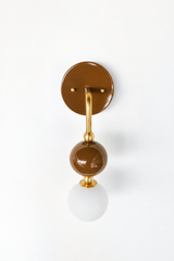 A deep chocolate-brown wall sconce for a bathroom, powder room, or bedroom that leads with warm, cozy color. The Ida sconce pairs a glossy brown powder-coated sphere with a frosted glass globe, joined by warm brass hardware and a round brown backplate. Rich and enveloping, it's a standout for eclectic, organic modern, Southern masculine, and colorful traditional homes that skip the safe answer.