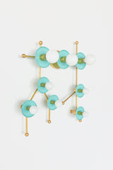 Front view studio image of the Gemini One sconce in Poolside and Brass, designed to look like the Gemini astrological constellation. Soft turquoise blue discs, white globe bulbs, and brass rods create a modern star map effect that reads as both lighting and wall art. This pastel constellation fixture is ideal for buyers looking for a colorful wall sconce, zodiac lighting, astrology decor, mid century modern wall light, nursery lighting, playroom lighting, dopamine decor, or a unique statement sconce for an 
