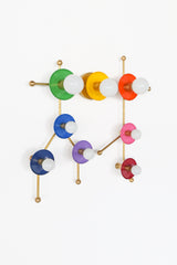This rainbow and brass Gemini One fixture is a vibrant modern wall sconce designed to echo the Gemini constellation in a bright, graphic way. The multicolor discs and warm brass structure give it a playful but elevated feel that suits quirky interiors, eclectic homes, children’s spaces, art-filled rooms, and bold designer projects. Ideal for those searching for colorful wall lighting, zodiac decor, constellation sconces, rainbow lighting, or a unique statement fixture for a maximalist or pop-inspired interi