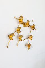 All-brass Gemini One wall sconce photographed on a clean white background, showing its constellation-inspired layout of brass rods, round star discs, and white globe bulbs. This modern celestial wall light feels sculptural, playful, and architectural, making it a strong fit for eclectic homes, kids rooms, nurseries, entryways, bedrooms, and design-forward interiors that need a brass statement sconce.