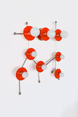 The Flame and Chrome Gemini One sconce is a bold, constellation-inspired wall light designed to echo the shape of the Gemini zodiac sign. This sculptural fixture features vivid flame-orange metal discs paired with polished chrome arms and white globe bulbs, creating a graphic, celestial silhouette that feels both playful and modern. Shown here in a studio setting against a clean white background, this colorful statement sconce works beautifully in eclectic interiors, maximalist spaces, creative studios, kid