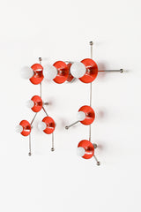 The Flame and Chrome Gemini One sconce is a bold, constellation-inspired wall light designed to echo the shape of the Gemini zodiac sign. This sculptural fixture features vivid flame-orange metal discs paired with polished chrome arms and white globe bulbs, creating a graphic, celestial silhouette that feels both playful and modern. Shown here in a studio setting against a clean white background, this colorful statement sconce works beautifully in eclectic interiors, maximalist spaces, creative studios, kid