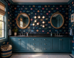 Moody blue coastal bathroom with patterned fish and shell wallpaper, teal painted cabinetry, black stone countertop, woven round mirrors, and a chrome Gemini One sconce styled as sculptural wall art above the double vanity. The fixture follows the Gemini star constellation, using chrome lines, round metal accents, and white globe bulbs for a playful celestial look. The room blends beach house decor, nautical wallpaper, colorful kids bathroom style, maximalist pattern, and modern chrome bathroom lighting.