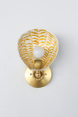 Sun-warmed elegance meets sculptural whimsy. This one-of-a-kind version of our Coquille Sconce features a hand-painted ceramic shell in soft cream, layered with golden ochre brushstrokes that ripple across its fluted form like morning light on water. Paired with detailed brass-toned hardware, this variation feels vintage, refined, and full of warmth.

As with our other One of One drops, this exact sconce won’t be repeated. It’s a functional art piece made for collectors of the strange, the beautiful, and th