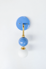 A soft periwinkle wall sconce for a bathroom, powder room, or bedroom that leads with gentle, romantic color. The Ida sconce stacks a glossy hydrangea-blue powder-coated sphere over a frosted glass globe, joined by warm brass hardware and a round periwinkle backplate. Pretty and calming without being sweet, it's a standout for Southern traditional, grandmillennial, Chinoiserie, and colorful traditional homes that skip the safe answer.