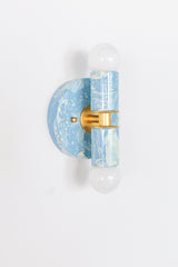 Small Thalia Sconce in a hand-marbled Hydrangea blue, Cream, and Gold finish, designed with a petite round backplate, cylindrical socket covers, brass accents, and globe bulbs. The soft colorway works beautifully in muted bathrooms, beach house powder rooms, children’s baths, chinoiserie-inspired spaces, and playful traditional interiors.