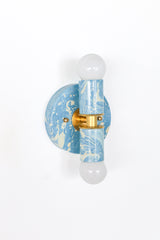 Small Thalia Sconce in a hand-marbled Hydrangea blue, Cream, and Gold finish, designed with a petite round backplate, cylindrical socket covers, brass accents, and globe bulbs. The soft colorway works beautifully in muted bathrooms, beach house powder rooms, children’s baths, chinoiserie-inspired spaces, and playful traditional interiors.