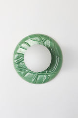 Green ceramic wall sconce in jade glaze, raised leaf motif backplate with frosted globe, sculptural botanical chinoiserie style on white background