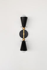 Black Janus Sconce with brass center column and accents, a bold geometric two light wall sconce with tapered cone shades and minimalist disc plates, photographed straight on with globe bulbs, a modern brutalist inspired wall light that installs vertical or horizontal, perfect for bathroom vanity lighting, mirror sconces, bedroom reading lights, entryway lighting, and designer modern home decor