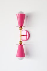This Doll Pink vanity sconce is meant to make a statement, whether it's mounted in pairs beside a bathroom mirror, lighting up a hallway, or adding color to a nursery. The double cone shape and brass ball hardware keep the silhouette clean and symmetrical, so the color gets to do the talking. A good option for anyone who wants lighting that reads as a real design choice, not an afterthought.