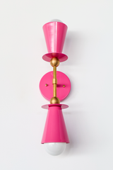 Installed as a pair, this Doll Pink vanity sconce brings warmth and color to a girl's bathroom, nursery, or powder room without tipping into anything too juvenile. The double cone shape and brass ball hardware give it a considered, mid-century feel, so it holds up as a real design choice rather than a themed one. Also works well flanking a bedroom mirror or as bedside wall lighting.