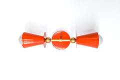 Janus horizontal wall sconce in flame orange with brushed brass hardware, double cone shades and globe bulbs, bold mid century modern wall light for maximalist interiors, dopamine decor, bathroom vanity lighting, bedside pair, hallway accent, or statement kids room lighting.