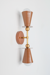 A single fudge-brown cone rises from a brass sphere, anchored to a circular backplate—a sconce that whispers rather than shouts. This streamlined version has all the warmth and sophistication of the Janus collection but in a more understated, focused form. The tapered shade directs light upward and outward; the brass sphere acts as a sculptural accent without dominating the profile. Perfect for a bedroom, hallway, or anywhere you want thoughtful, collected-feeling lighting that doesn't demand attention but 