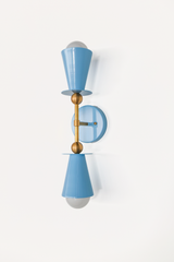This vertical bath bar sconce is built to flank a bathroom mirror in pairs, with two hydrangea blue cone shades and brass ball hardware giving it a mid-century, Art Deco-adjacent shape. The soft periwinkle tone fits naturally into a coastal or Southern traditional space, a nursery, or a powder room. Symmetrical shape, gentle color, made to actually get noticed instead of disappearing into the wall.
