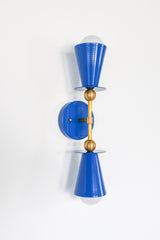This angled view highlights the Janus Sconce's sculptural construction, revealing the depth and balance of its symmetrical double-cone design. Finished in Mediterranean blue with warm brass accents, it blends bold color with refined geometry for colorful traditional homes, eclectic interiors, Art Deco-inspired spaces, and designer-led projects that celebrate personality over predictable lighting.