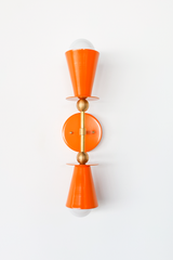 This vertical bath bar sconce is built to flank a bathroom mirror in pairs, with two Orange Peel cone shades and brass ball hardware giving it a mid-century, Art Deco-adjacent shape. It works as vanity lighting in a powder room, as an accent in a kitchen or breakfast nook, or as hallway sconces. Bold color, symmetrical shape, made to actually get noticed instead of disappearing into the wall.