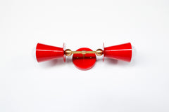 Both cone shades of this red and brass vanity sconce face the camera here, showing the exposed bulb on each side of the backplate. In a real bathroom, this fixture mounts vertically and is typically installed as a pair flanking a mirror, so this symmetrical view is a good preview of how balanced the two sides look next to each other. Works equally well in a powder room, hallway, or as bedside lighting.
