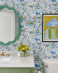 A charming, kid-friendly bathroom featuring our Adele Two Light Sconce in Poolside and brass, styled against whimsical blue and green animal wallpaper for a fun, storybook feel. The playful space pairs a scalloped green mirror, soft green vanity, white marble countertop, brass faucet, and framed artwork for a colorful yet polished look. With its soft blue backplate and warm brass arms, the Adele sconce adds a cheerful glow that works beautifully in kids bathrooms, powder rooms, playful family homes, and ecl